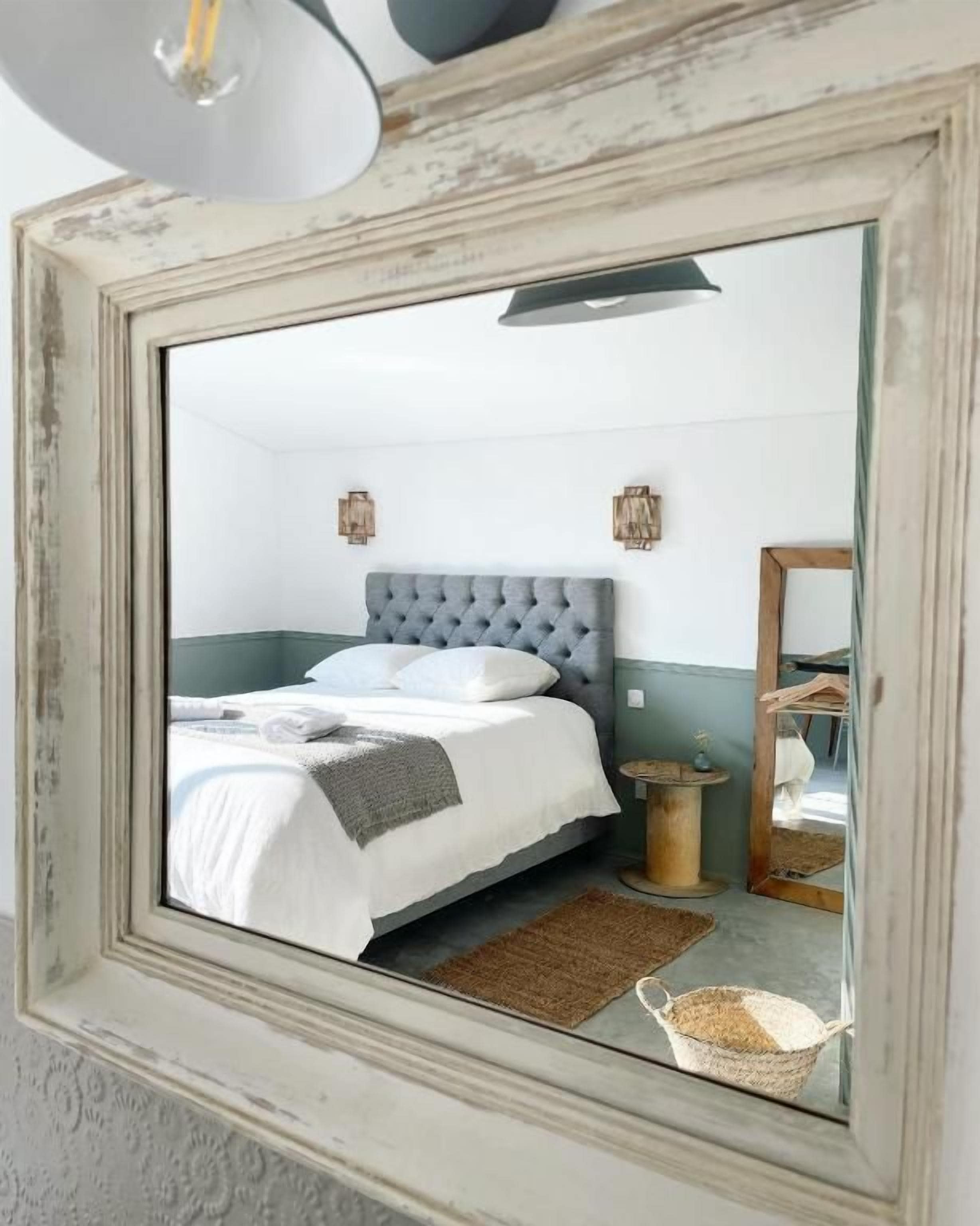 Una camera da letto con un letto, un comodino, una lampada e uno specchio.