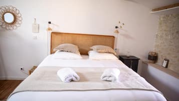 A neatly made bed with two pillows, a bedside table with a lamp, and a wall-mounted mirror.
