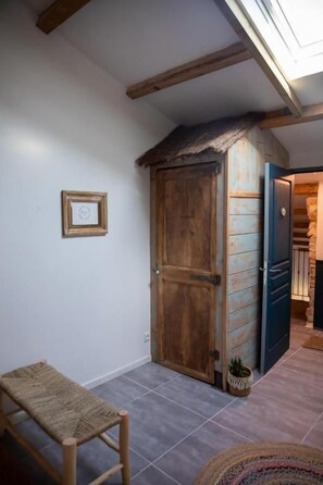 A room with a wooden door, a bench, and a small potted plant.