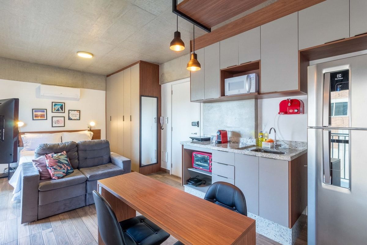 A compact living space with a kitchenette, a sofa, a dining table, and a TV.