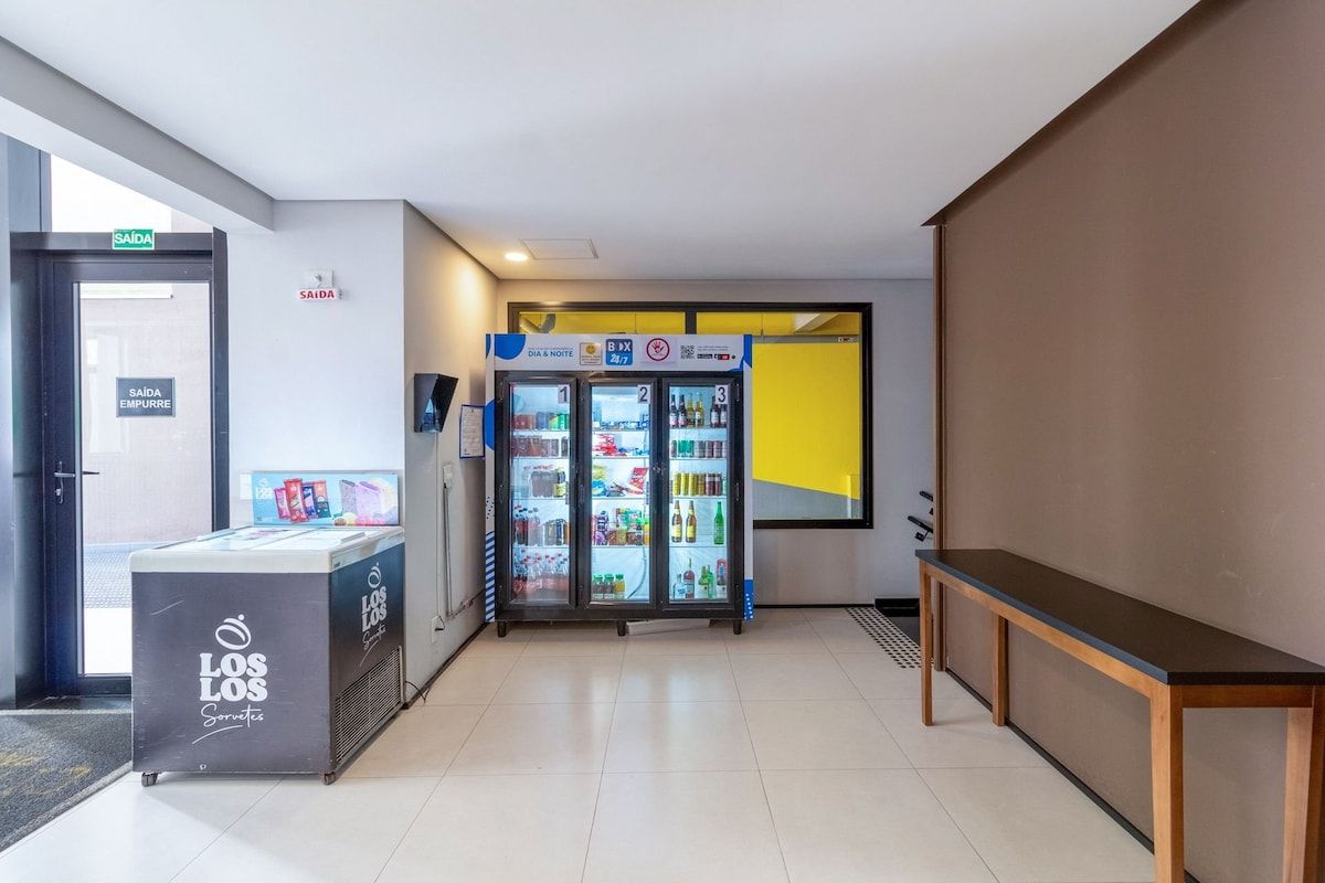 A hallway with a vending machine, a refrigerator, and a bench.