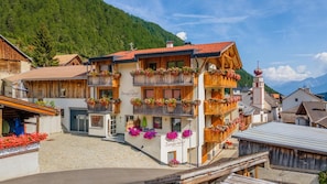 Ein mehrstöckiges Hotel mit hölzernen Balkonen, die mit Blumen geschmückt sind, vor einer Bergkulisse.