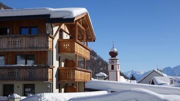 Eine Holzhütte mit Balkon, Glockenturm und Bergblick.