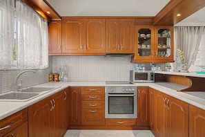 A compact kitchen with wooden cabinets, a built-in oven, a microwave, and a sink.