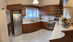 A modern kitchen with stainless steel appliances, wooden cabinets, and a white countertop. - Country House 'Ochra' with Mountain View, Wi-Fi and Air Conditioning (δημοτική ενότητα Λουτρακίου-Περαχώρας)