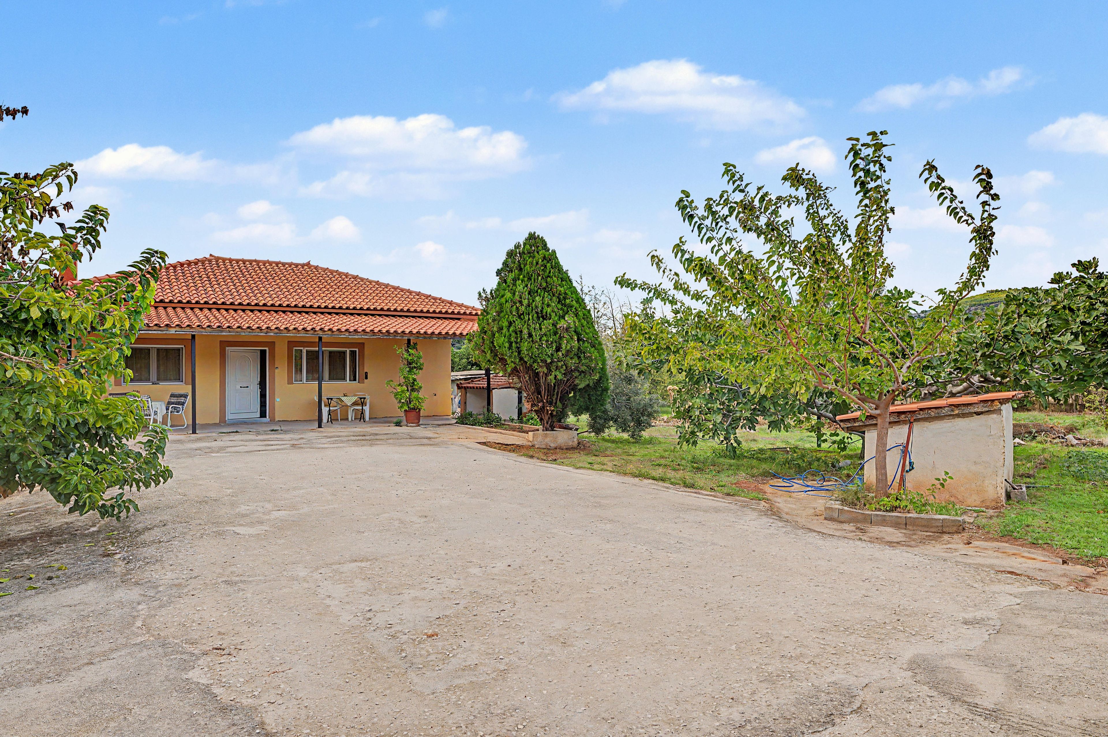 A two-story house with a tiled roof, a front yard, and a small garden area.