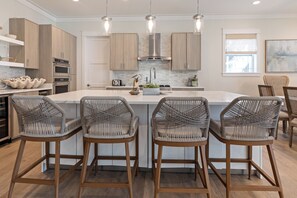 A modern kitchen with a central island, bar stools, built-in appliances, and pendant lighting. - Out of Office Beaches | Lagoon Pool, 7 Bikes, Screened Balcony, Sleeps 14 (Seacrest Beach)