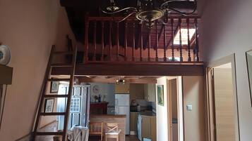 Un interior de varios niveles con una escalera, un comedor y una cocina.