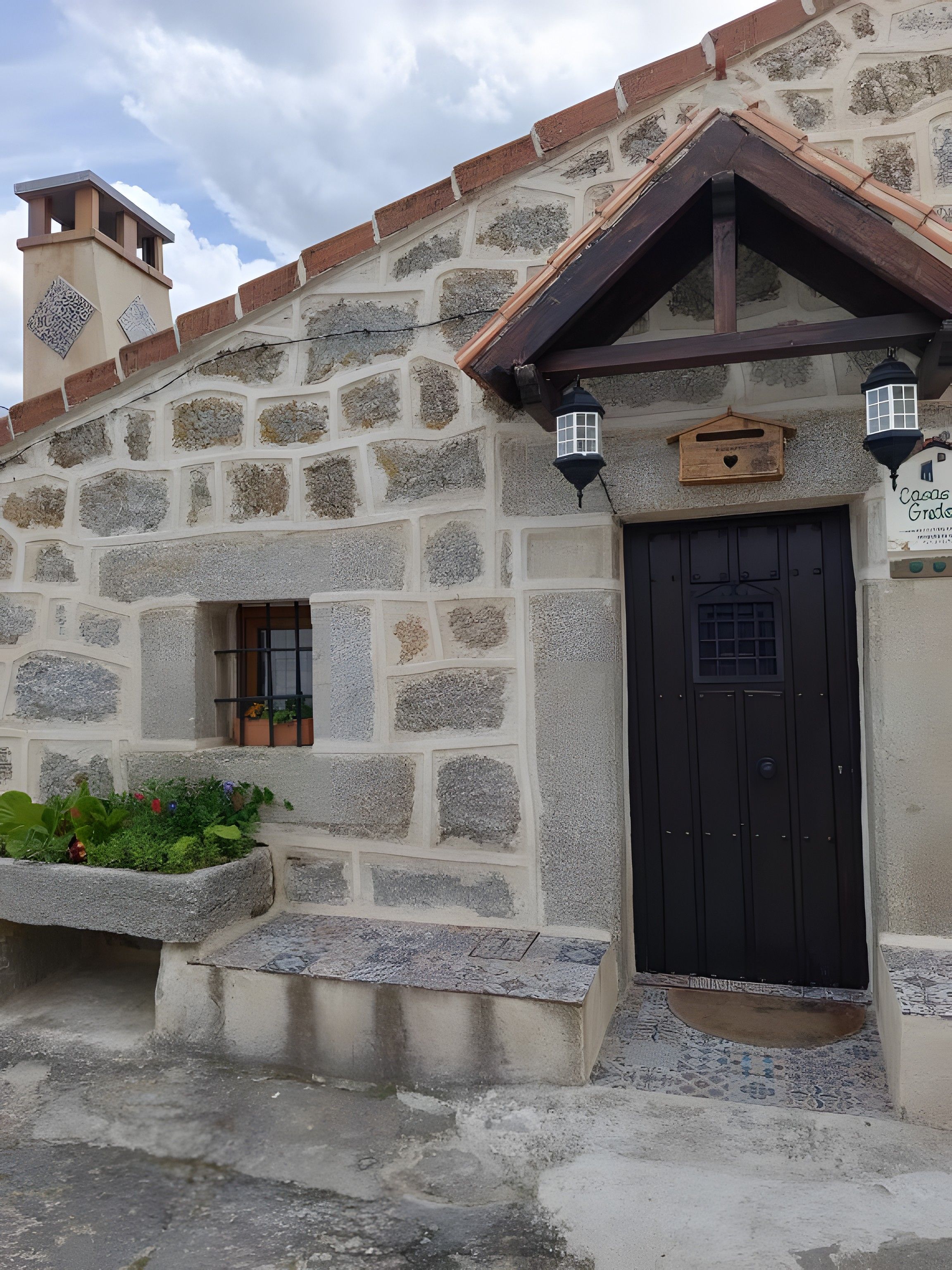 Un edificio de piedra con una puerta negra, un ventanal pequeño y un letrero que dice 'Casa Granda'.