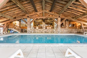 An indoor swimming pool with stone pillars, wooden beams, and a view of the interior. - Wifi, 50m from ski slopes, view building, fitness, swimming pool, sauna, hammam, balcony, ski locker (Les Arcs)