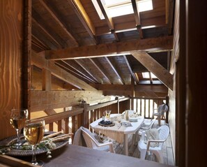 A wooden dining area with a table set for two, featuring white chairs and a glass of wine. - Wifi, 50m from ski slopes, view building, fitness, swimming pool, sauna, hammam, balcony, ski locker (Les Arcs)
