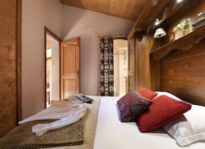 A wooden room with a bed, a small table, and a door leading to another room. - Wifi, 50m from ski slopes, view building, fitness, swimming pool, sauna, hammam, balcony, ski locker (Les Arcs)
