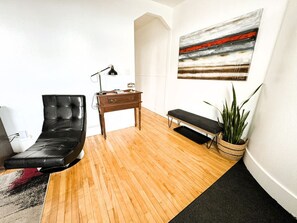 Ein modernes Wohnzimmer mit Ledersessel, Holzschreibtisch, Bank und Blumentopf.