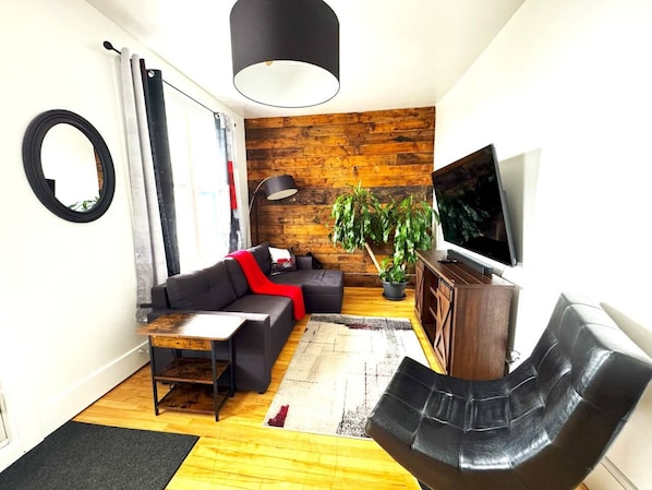 Una sala de estar moderna con un sofá, una mesa de centro, un televisor y una planta.