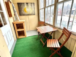 Una habitación con piso de césped artificial verde, muebles de madera y un ventanal con vistas a un paisaje nevado.