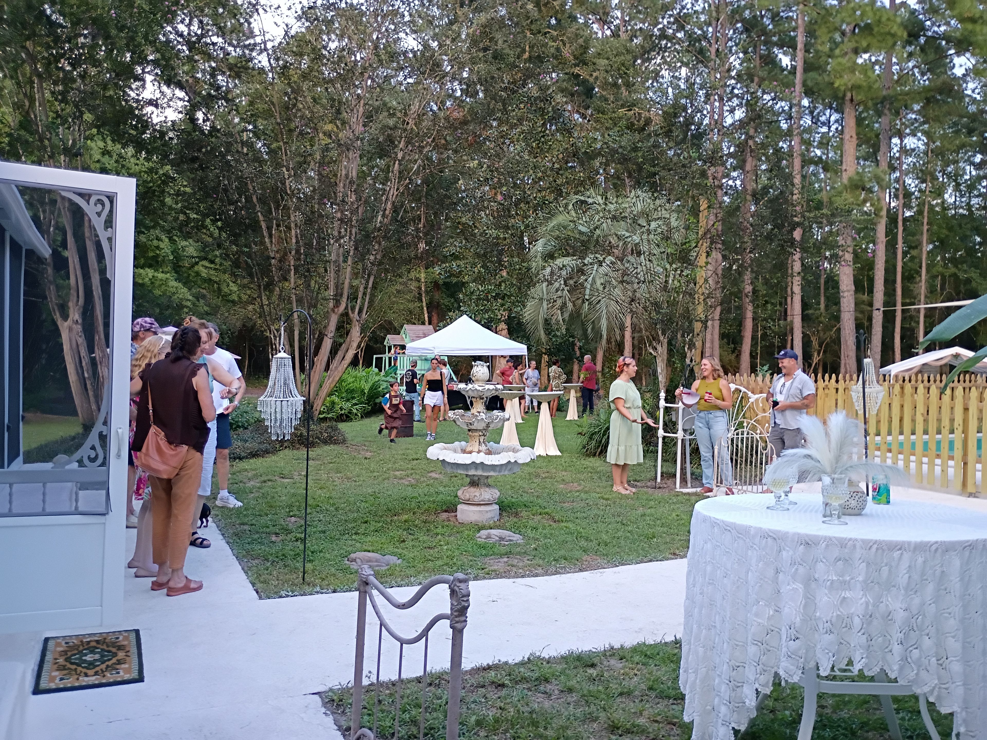 Evento al aire libre con una carpa, mesas y una fuente decorativa.