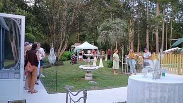 Evento al aire libre con una carpa, mesas y una fuente decorativa.