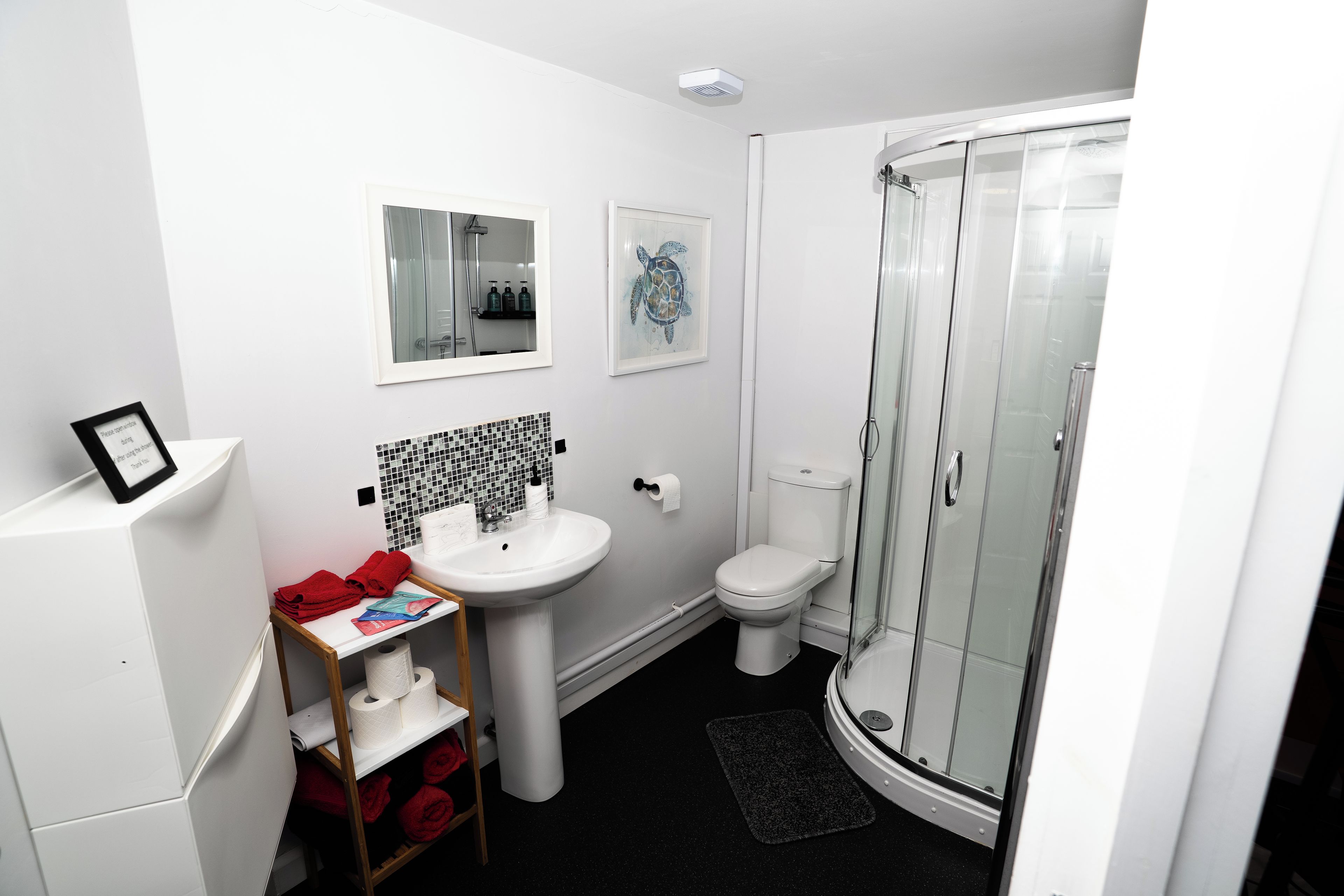 Une salle de bain avec un lavabo blanc, des toilettes et une cabine de douche en verre.