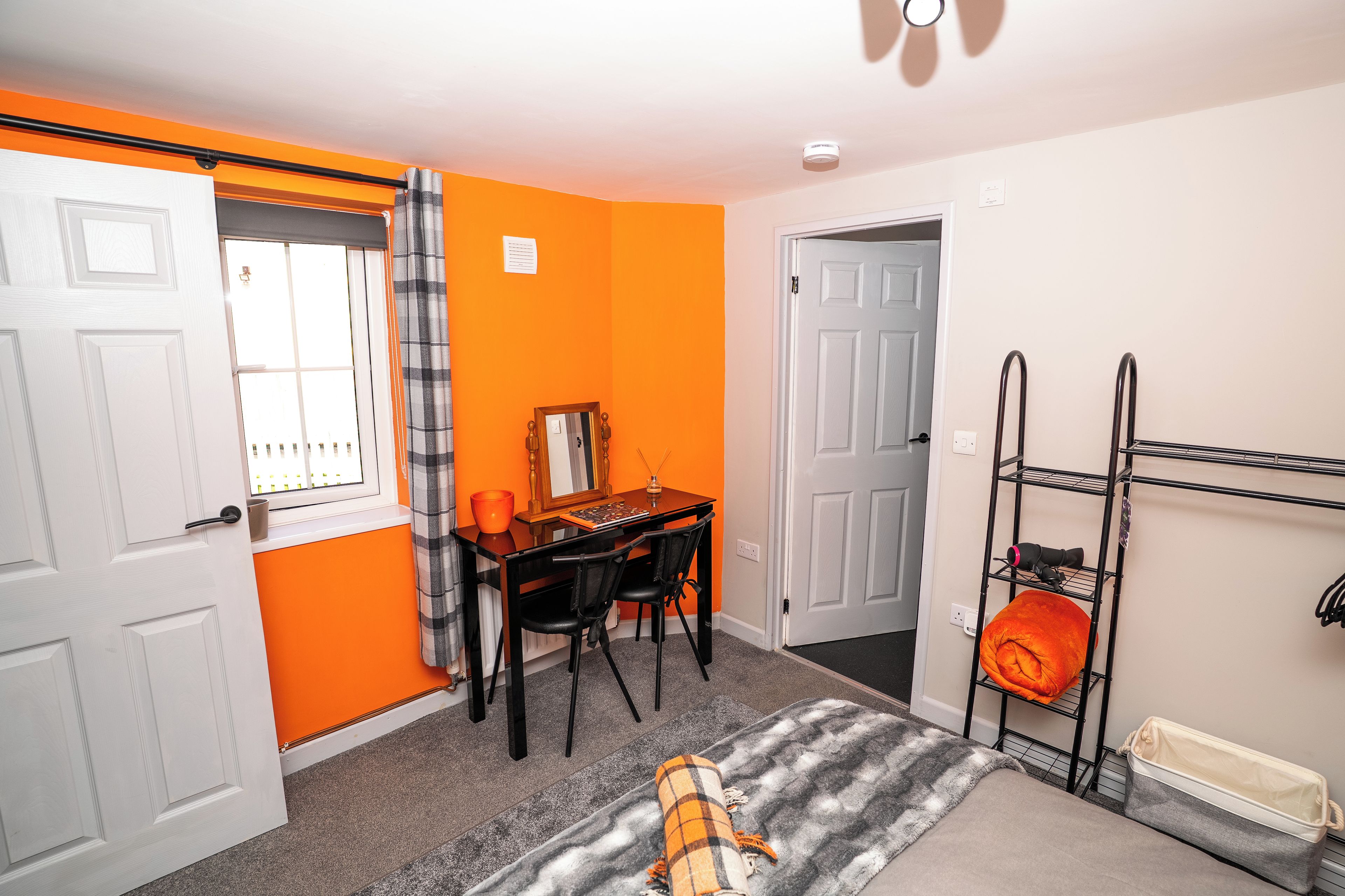A room with a desk, chair, and a bunk bed with a storage shelf.