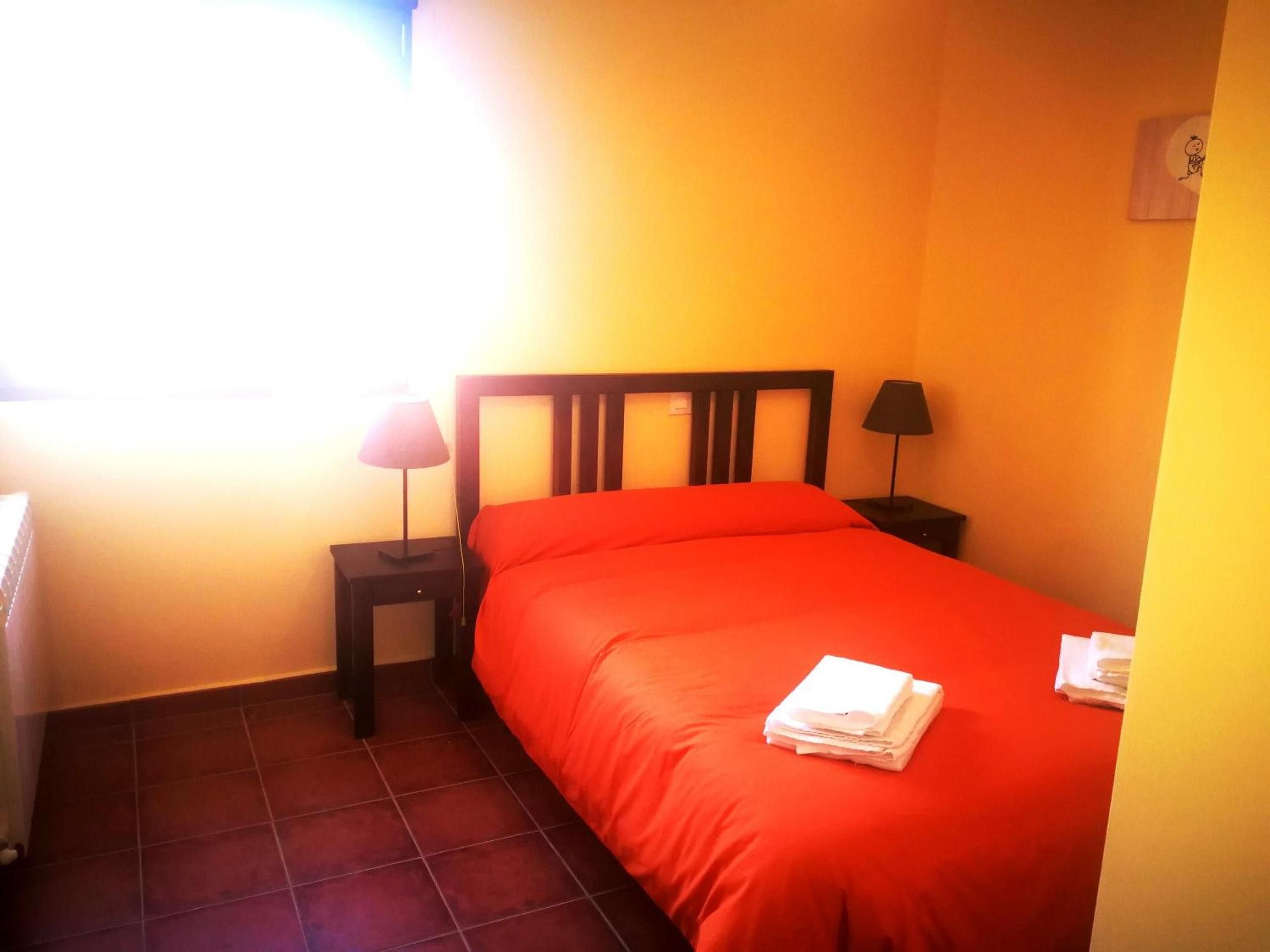 Une chambre avec un lit, deux tables de chevet et une fenêtre.
