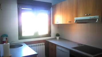 Una cocina con ventana, radiador, lavavajillas y armarios de madera.