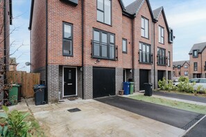 A residential building with a brick facade, black-framed windows, and a gated driveway. - Stylish 5-Bed for 12 w/ Pool & Table Tennis Near Etihad & Co-op Live (Droylsden)