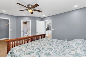 A bedroom with a bed, a ceiling fan, and a bathroom visible through an open door. - Lovely 2-bedroom house with AC in charming Englewood with Boat slip to Lemon Bay (Englewood)