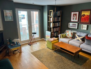 A living room with a sofa, coffee table, and a bookshelf. - One Double Room in Holyrood Apartment (Edinburgh)