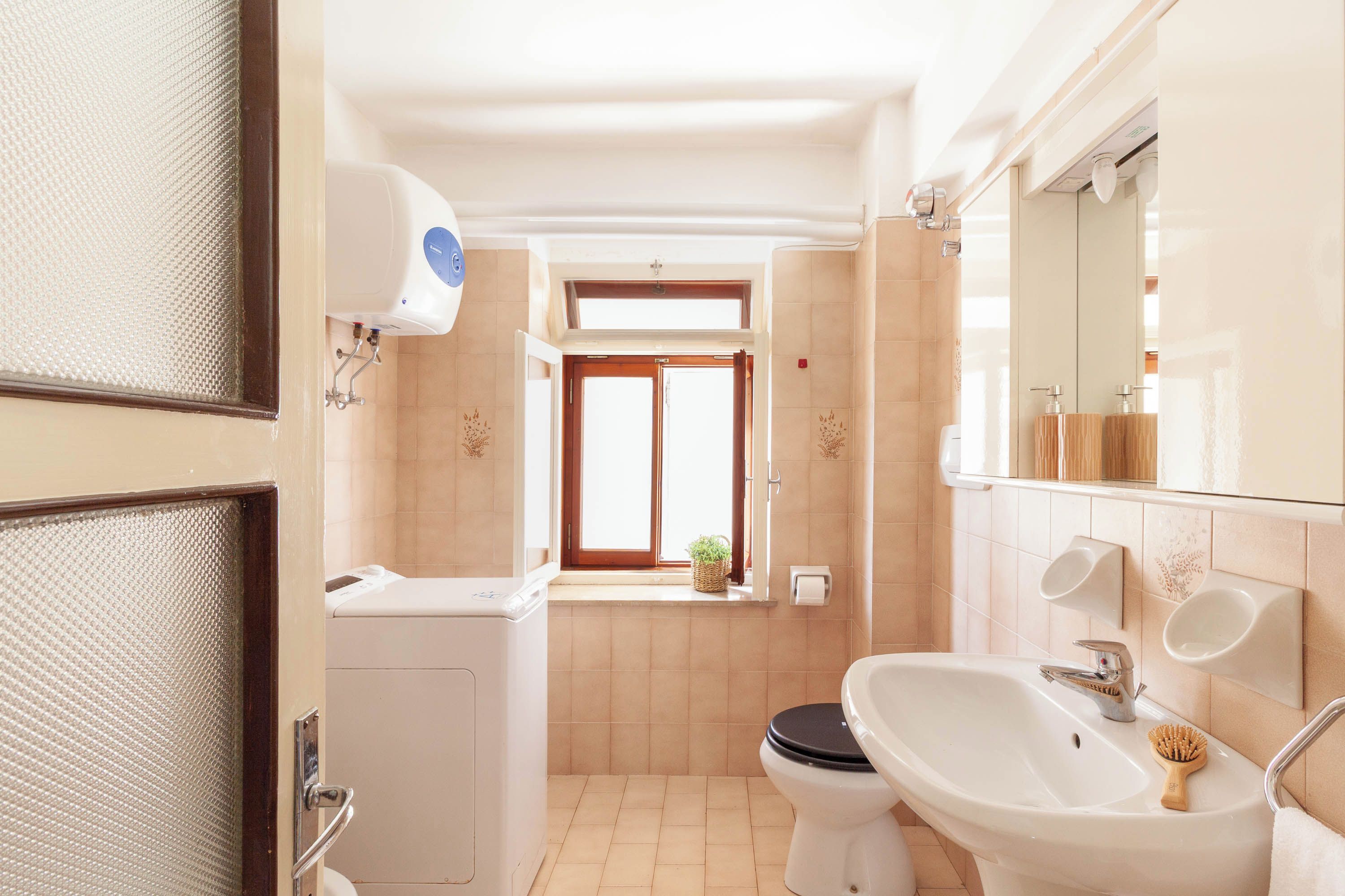 Une salle de bain avec des toilettes, un lavabo et une fenêtre.