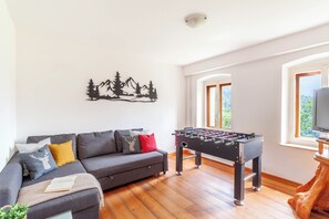 Un salon avec un canapé, une table de baby-foot et un téléviseur.