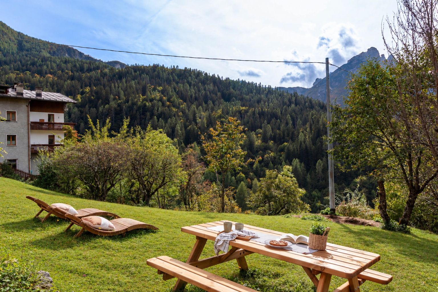 Un montaje para picnic con una mesa y sillones de descanso en una colina cubierta de césped, con montañas al fondo.