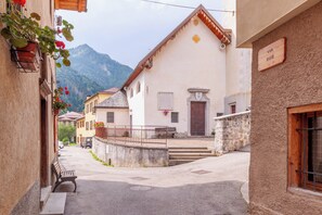 Un carrer estret amb edificis a ambdós costats, una panxa de rata i una muntanya al fons.