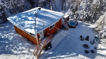 A cabin with a covered deck, a fire pit, and outdoor seating.