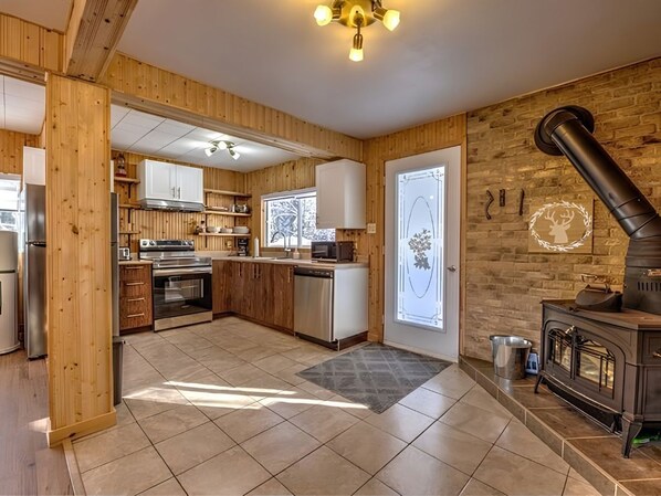 Una cocina moderna con paneles de madera, estufa empotrada y un ventanal grande.