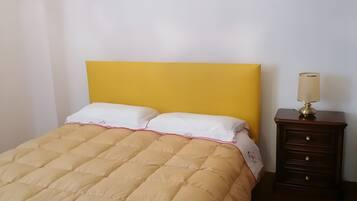 Ein Schlafzimmer mit einem Bett, einem Nachttisch, einer Lampe und einem Kronleuchter.