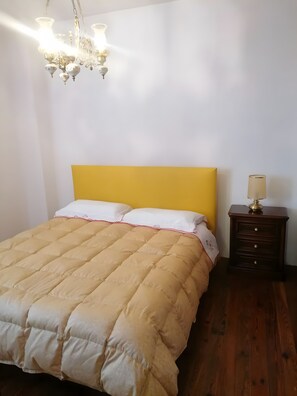 Ein Schlafzimmer mit einem Bett, einem Nachttisch, einer Lampe und einem Kronleuchter.