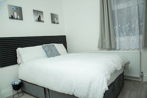 Ein Bett mit weißer Bettdecke, einem schwarzen Kopfteil und einem einzelnen Zierkissen.