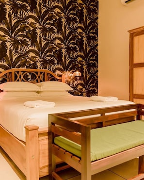 A single bed with a wooden frame and a green cushion, a wooden bench, and a wall with a tropical leaf pattern. - RELAX AND UNWIND AT LU XURY MODERN VILLA DC (Talpe)
