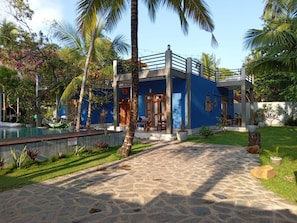A two-story building with a blue exterior, a stone pathway leading to the entrance, and a pool area with a hammock. - RELAX AND UNWIND AT LU XURY MODERN VILLA DC (Talpe)