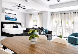 A modern hotel room with a bed, a sofa, a dining table, and a ceiling fan. - Sol Harbour Apartment in Ocho Rios (Ocho Rios)