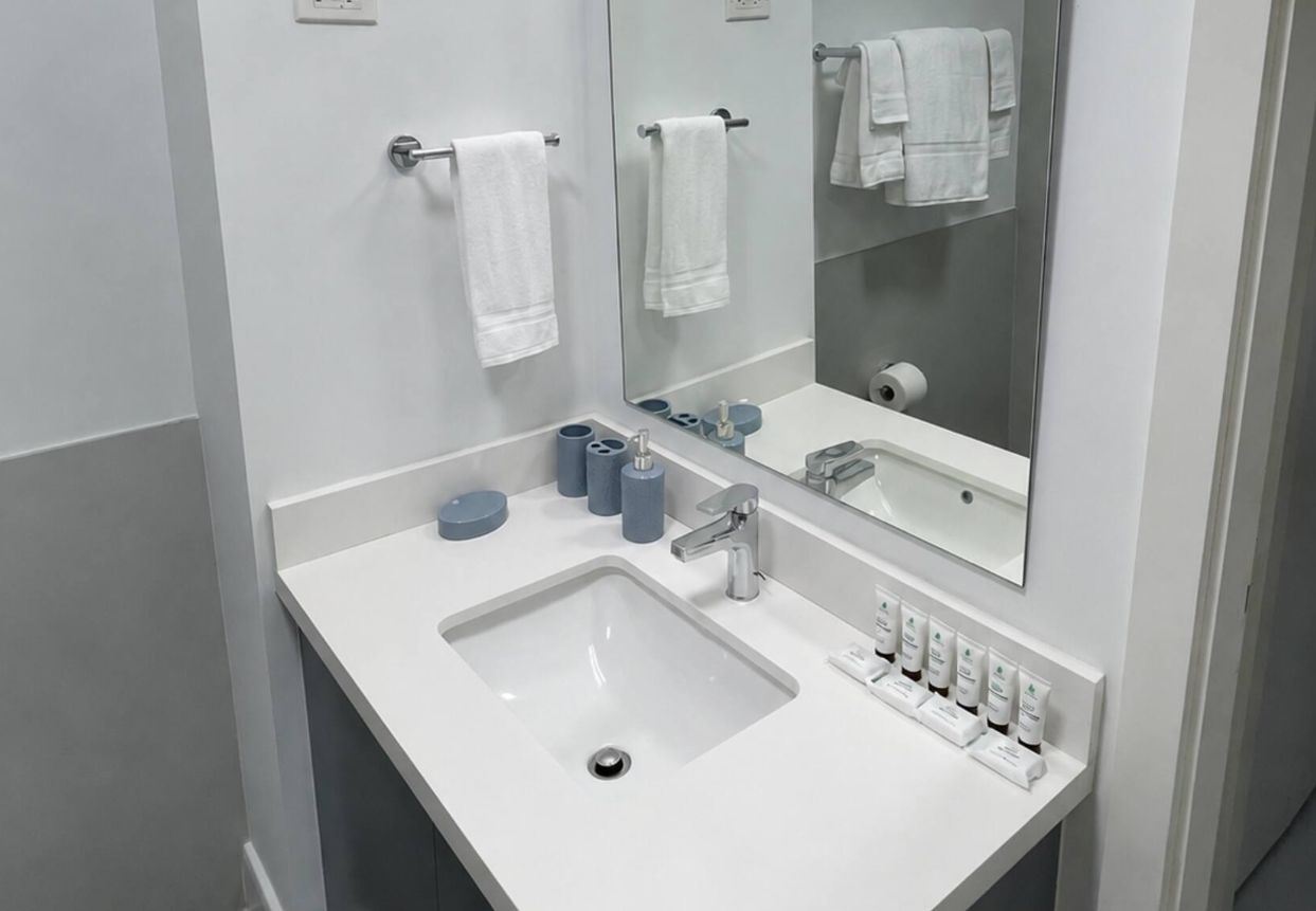 A modern bathroom with a white sink, a mirror, and a towel rack.