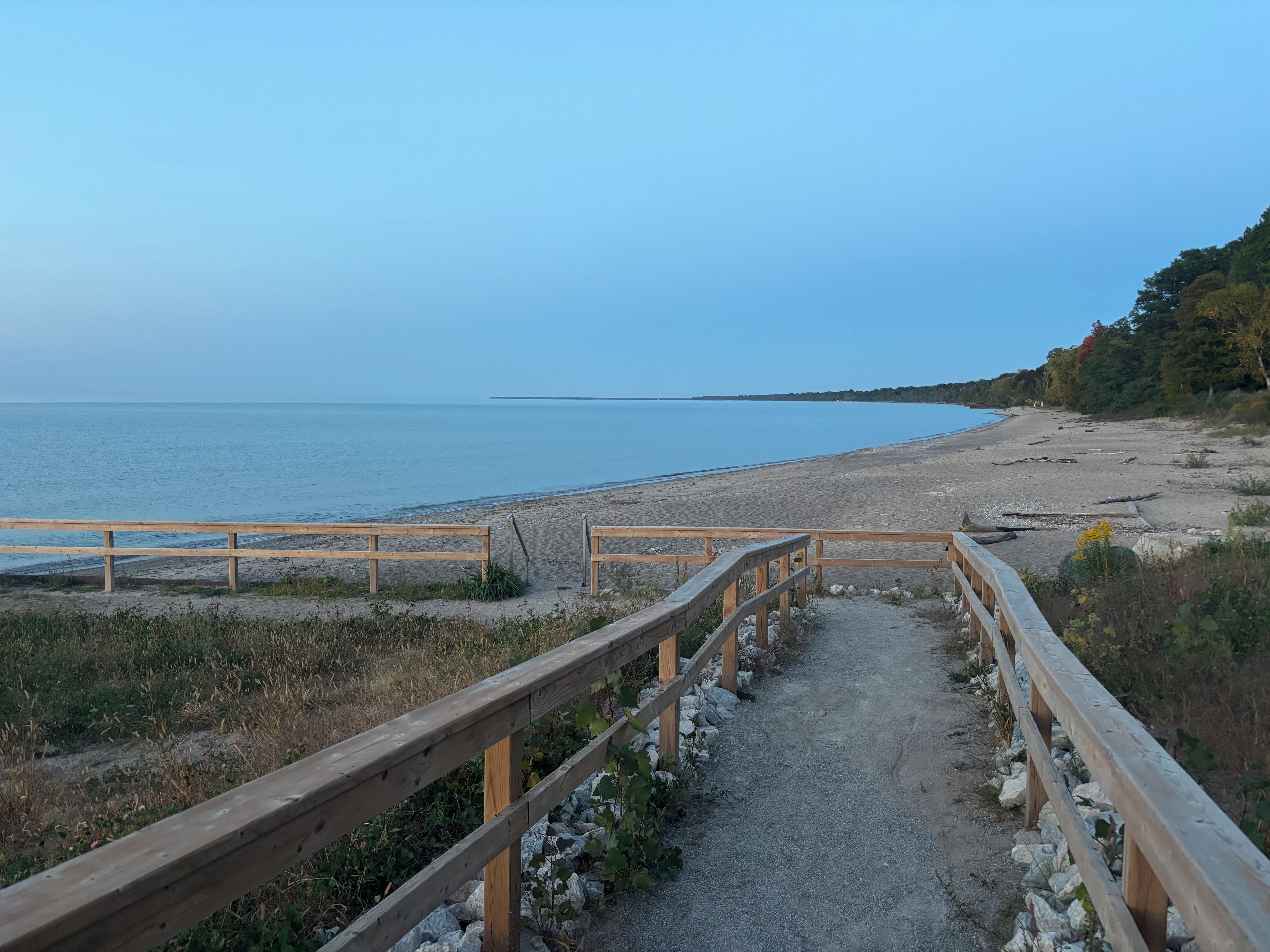 A wooden pathway leading to a beach with a clear view of the sea.