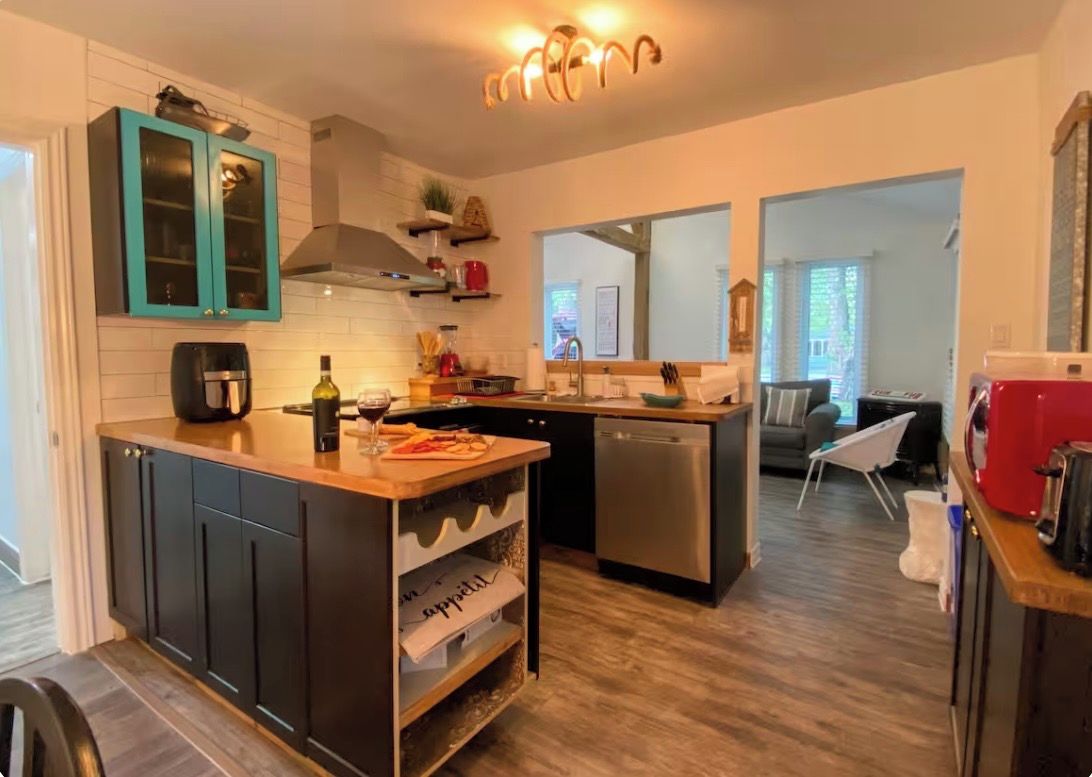 A modern kitchen with dark cabinetry, a central island, and a dishwasher.