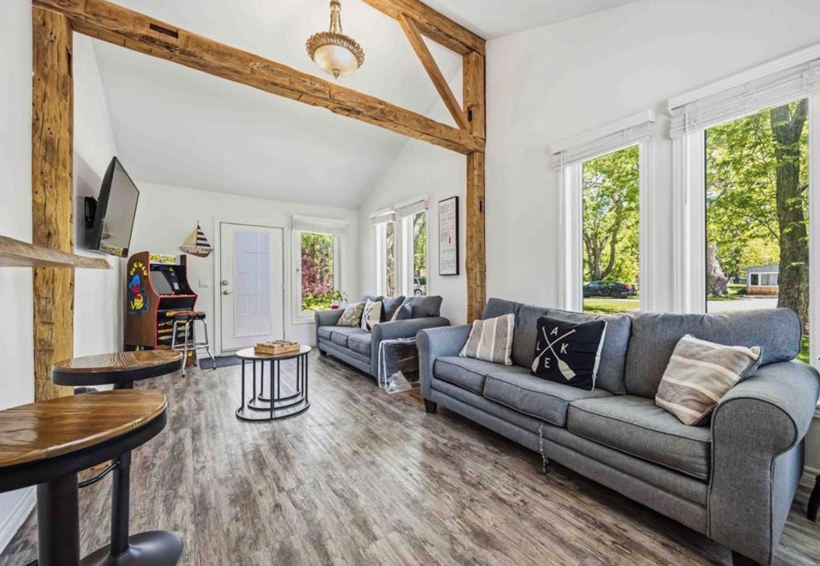 A spacious living area with a large sofa, wooden beams, and a television.