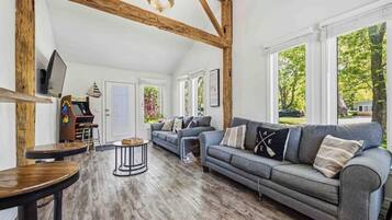 A spacious living area with a large sofa, wooden beams, and a television.