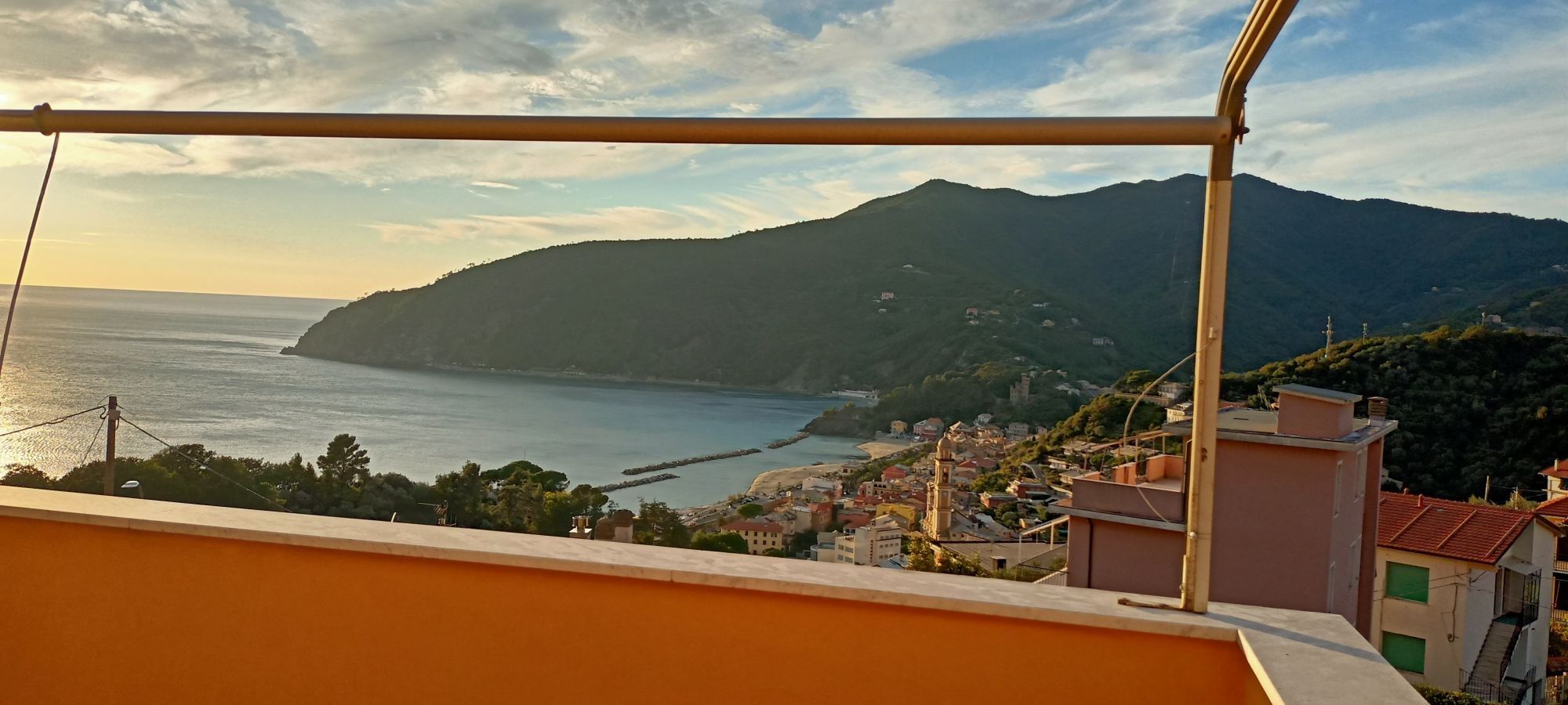A coastal town with buildings, a sea view, and a mountain in the background.