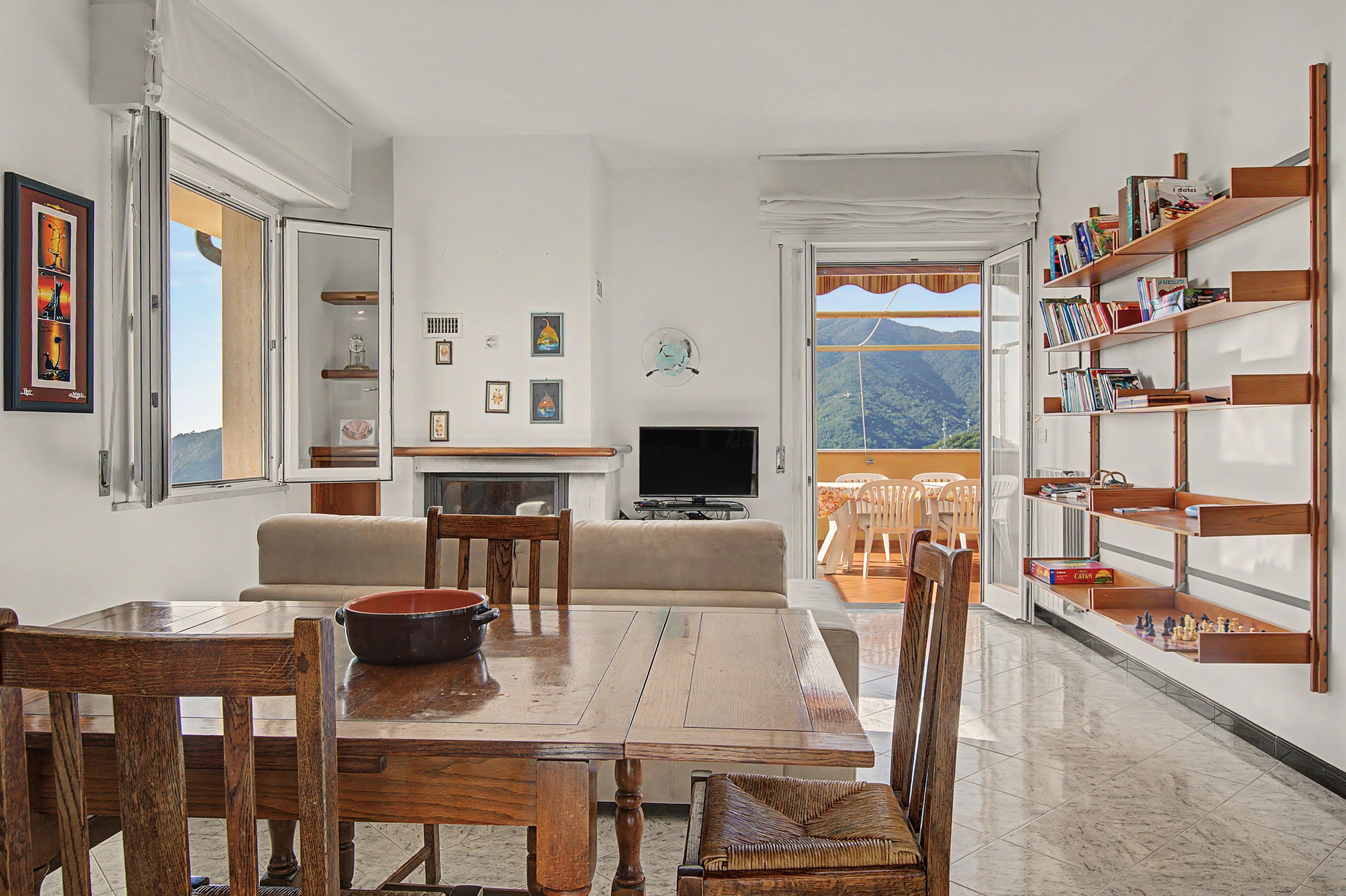 Ein Wohnzimmer mit Essbereich, Fernseher und Bücherregal.