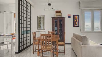 A dining area with a wooden table and chairs, a cabinet with glass doors, and a white sofa.