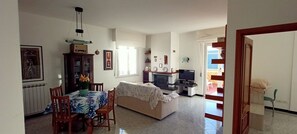 Un salon comprenant un canapé, un téléviseur et un coin repas avec des chaises et une table.