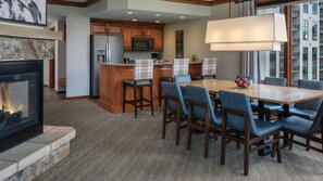 Una cocina moderna con armarios de madera, una isla central y una zona de comedor con sillas azules.